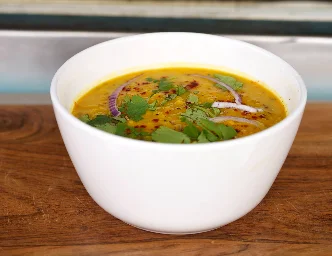 Bowl of creamy daal lentil soup topped with ghee and spices